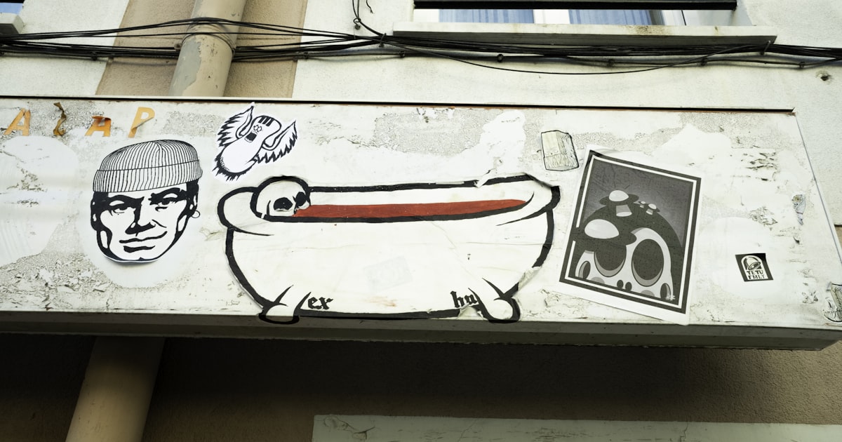 Graffiti art on a building exterior with bathtub illustration.