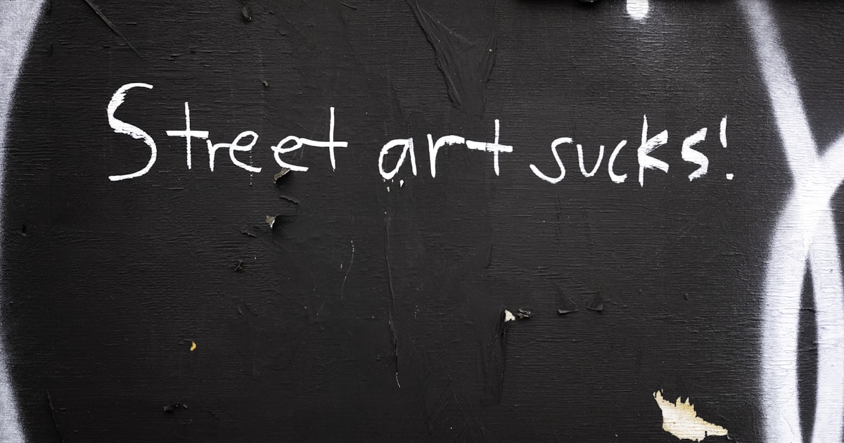 Street art sucks text written on a dark wall