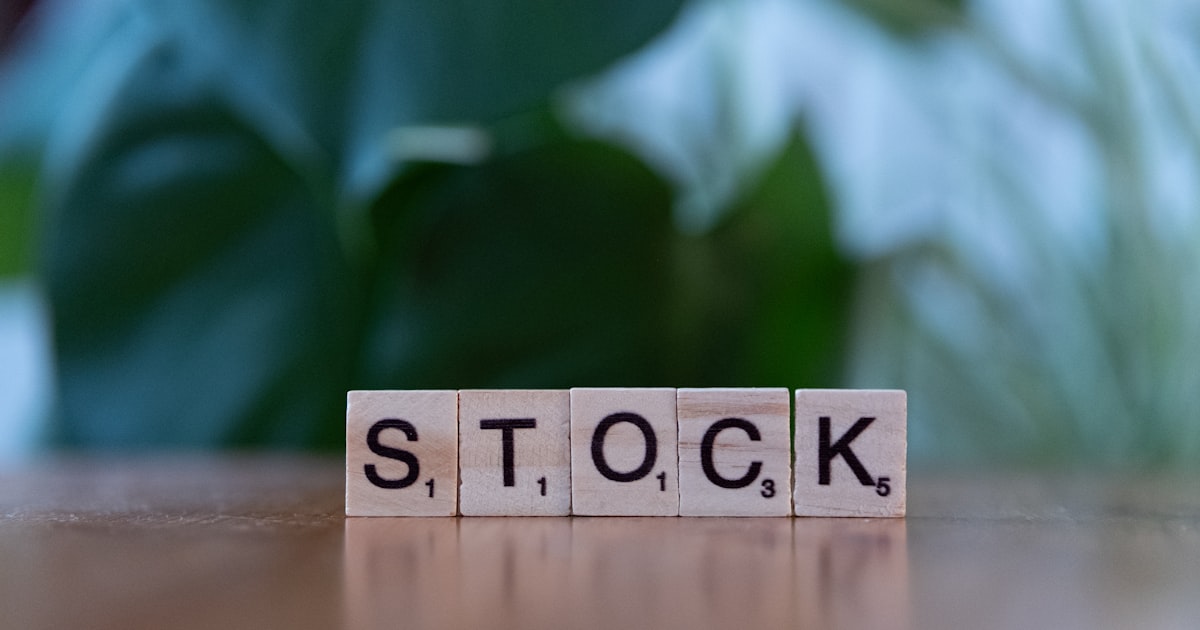 A wooden block spelling the word stock on a table
