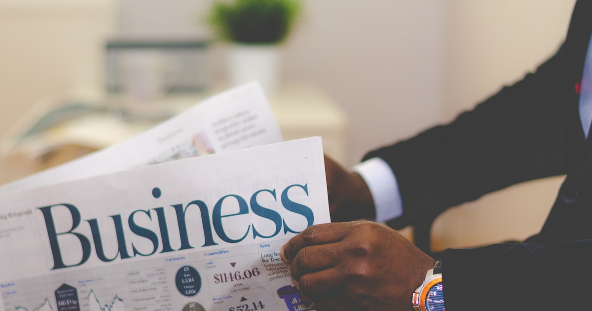person wearing suit reading business newspaper