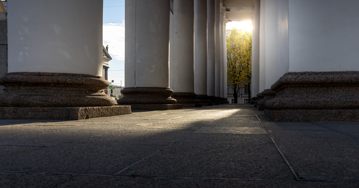 Sunlight streams through classical columns at dawn.