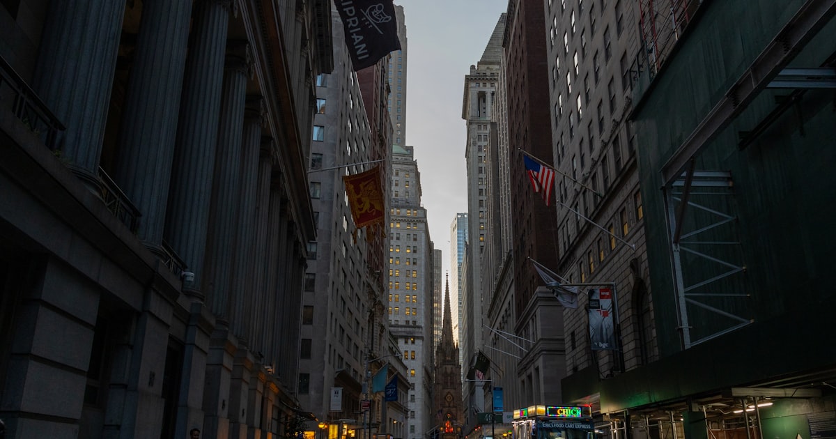 A city street with tall buildings and people walking down it