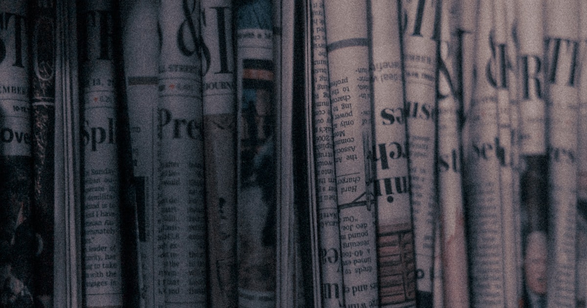 a row of newspapers sitting on top of a shelf