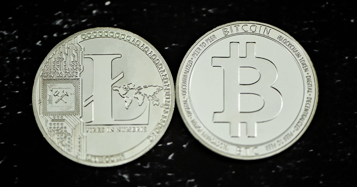 two silver bitcoins sitting on top of a black table