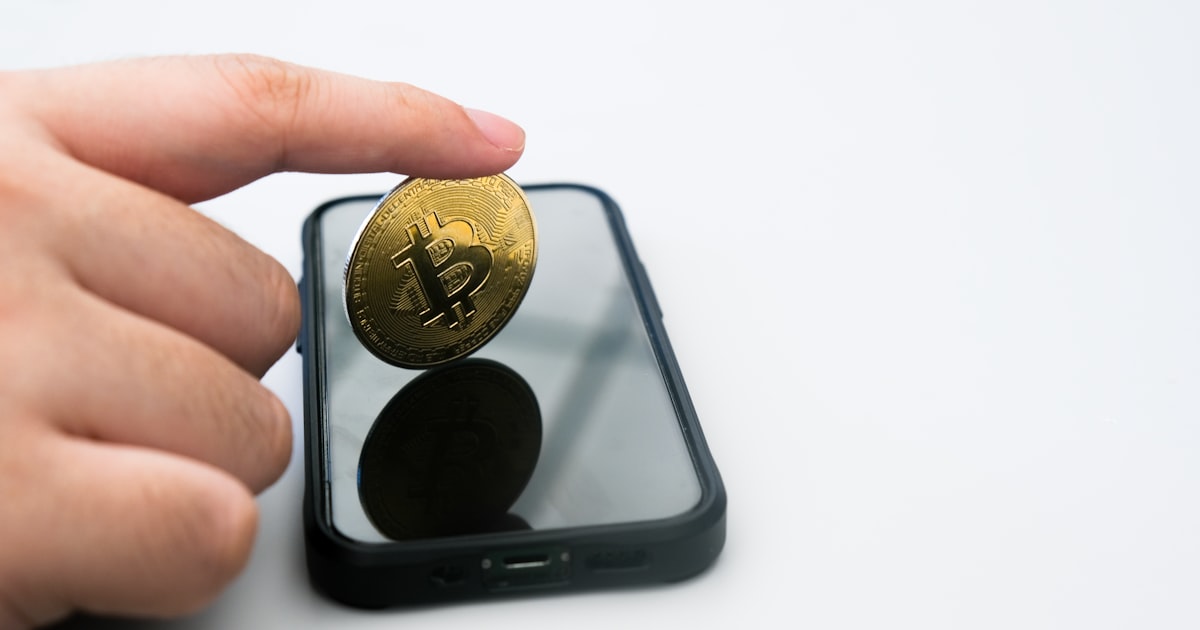 a person holding a gold coin in front of a cell phone