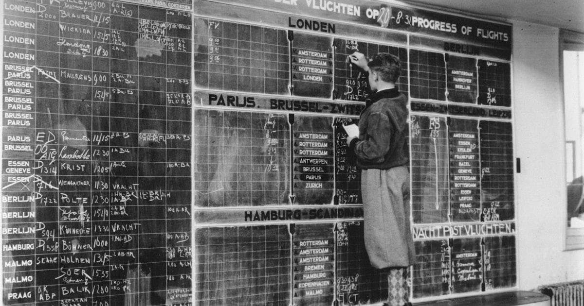 Man updates flight departure board with chalk