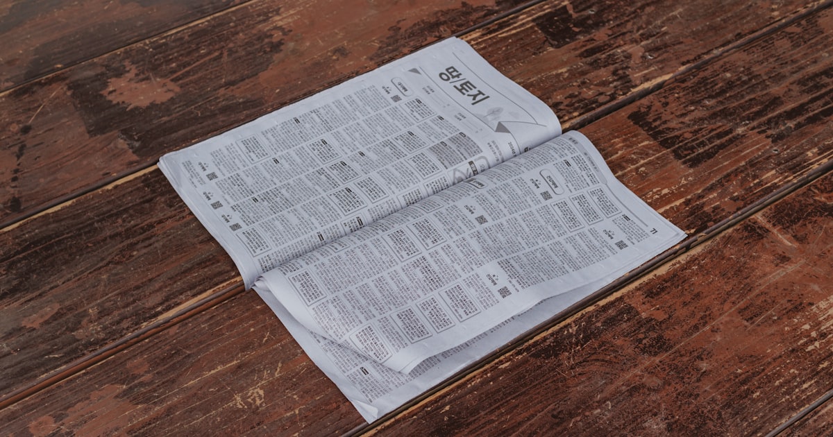 Open newspaper lying on a rustic wooden floor