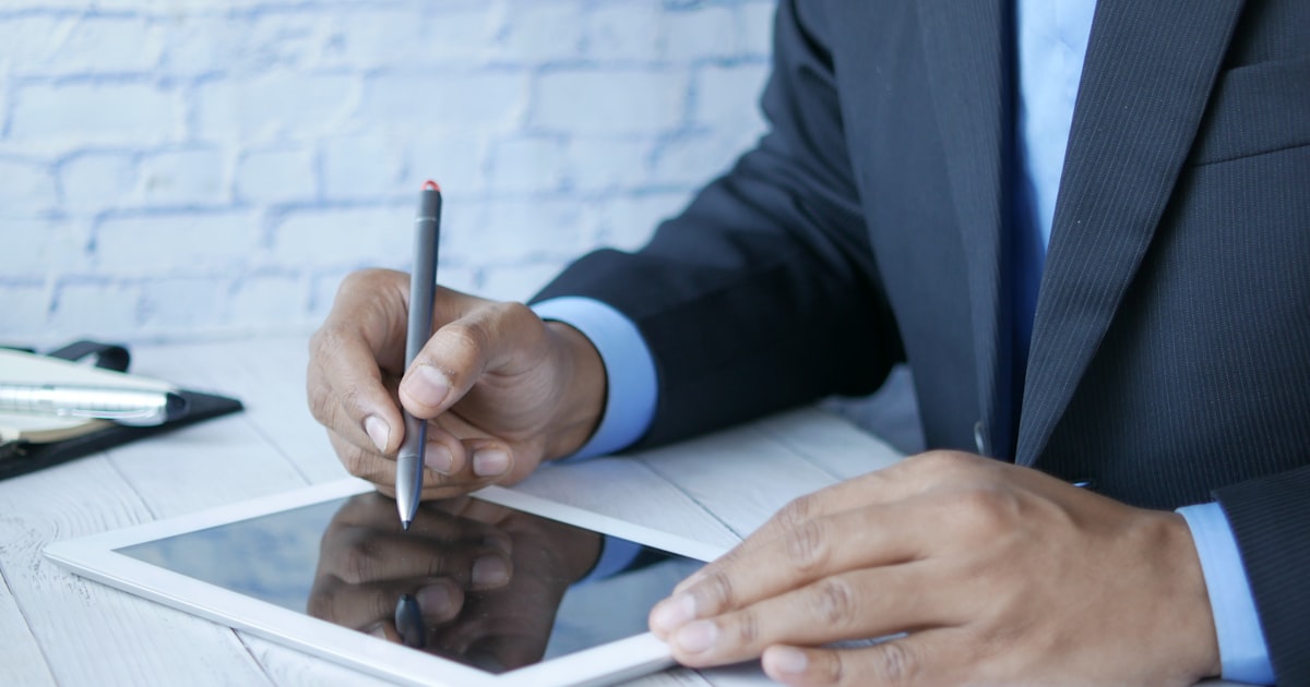 a man in a suit writing on a tablet