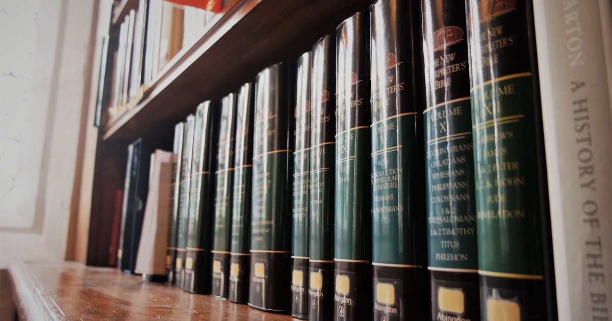 a row of books sitting on top of a wooden shelf