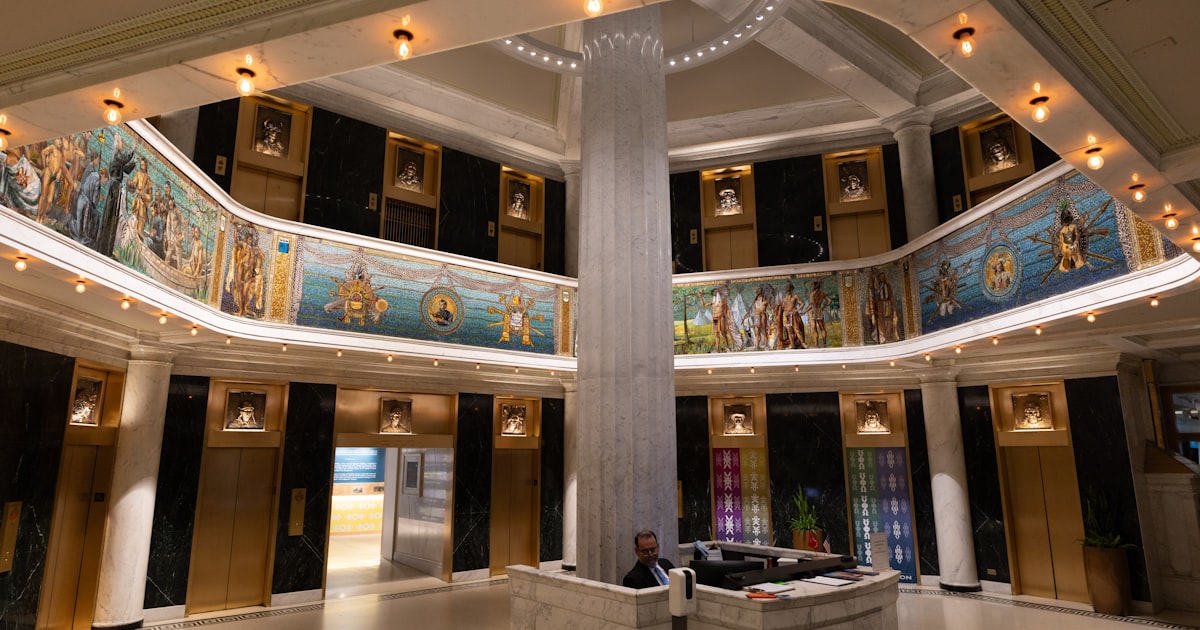 Ornate hall with murals, central pillar, and reception desk.
