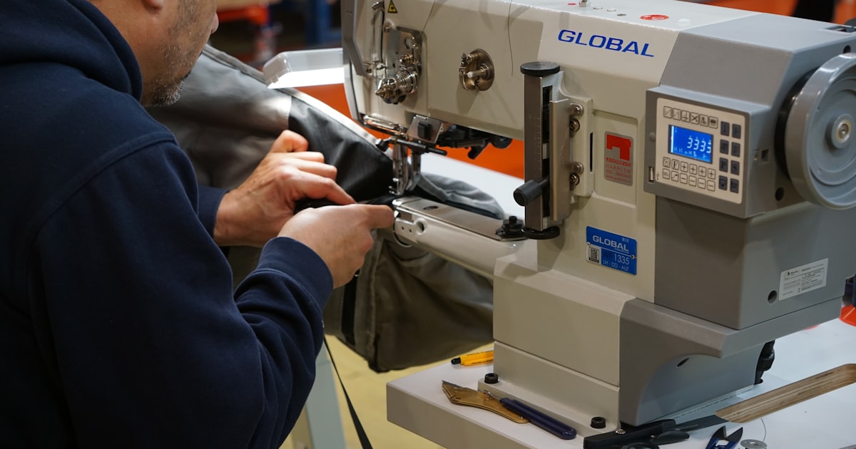 Man sewing fabric on industrial sewing machine.