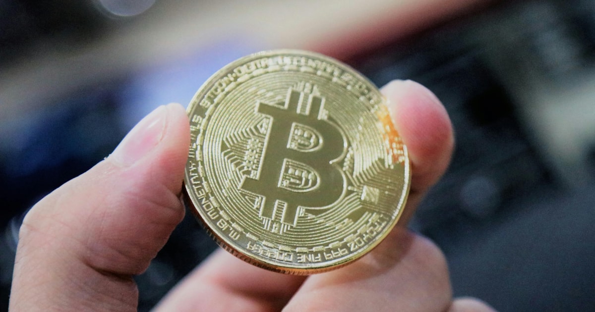 A hand holds a bitcoin.