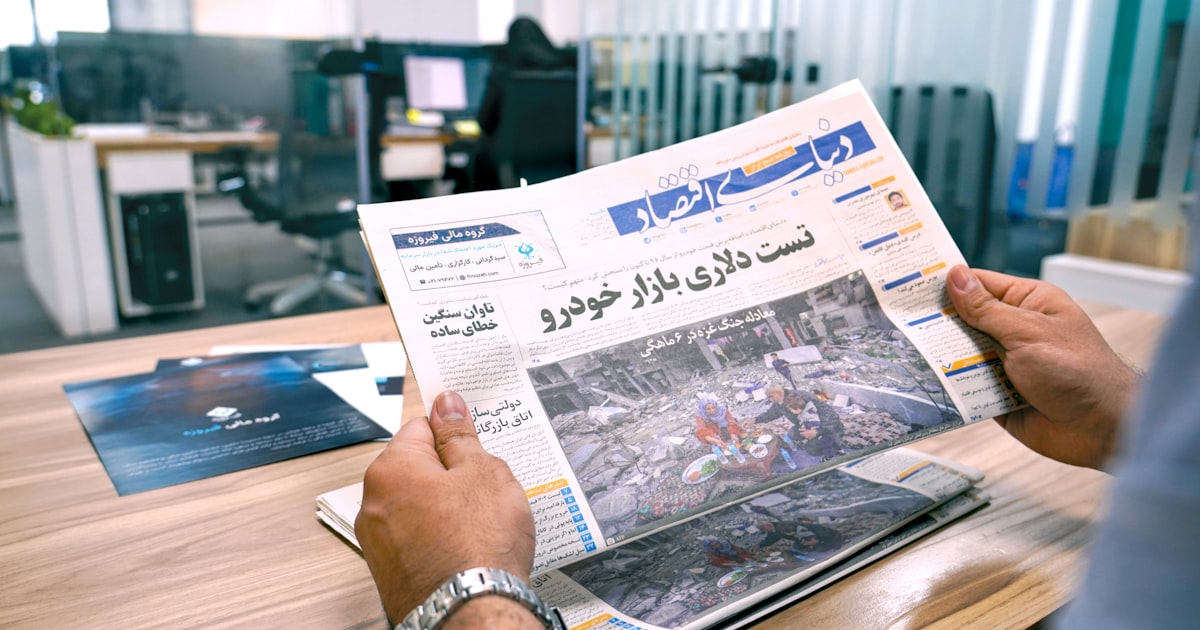 a man sitting at a table reading a newspaper