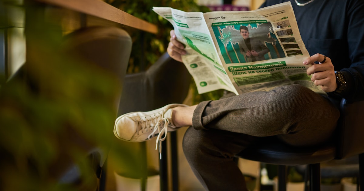 a man sitting in a chair reading a newspaper