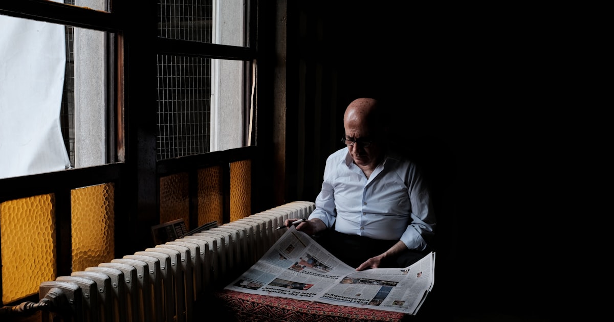 man in white dress shirt reading newspaper