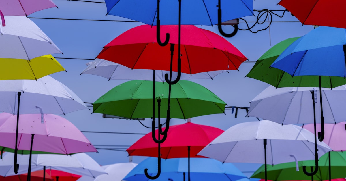Colorful umbrellas hang against a blue sky.