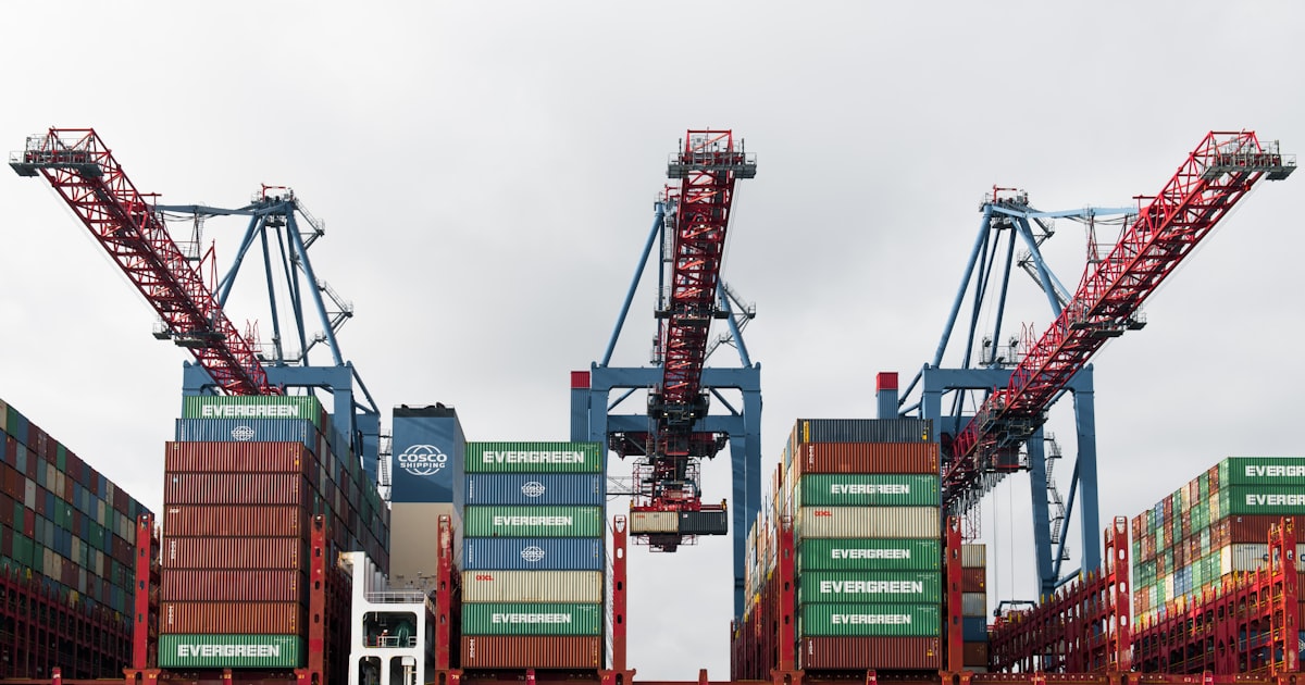 Cargo cranes loading shipping containers onto a large vessel.
