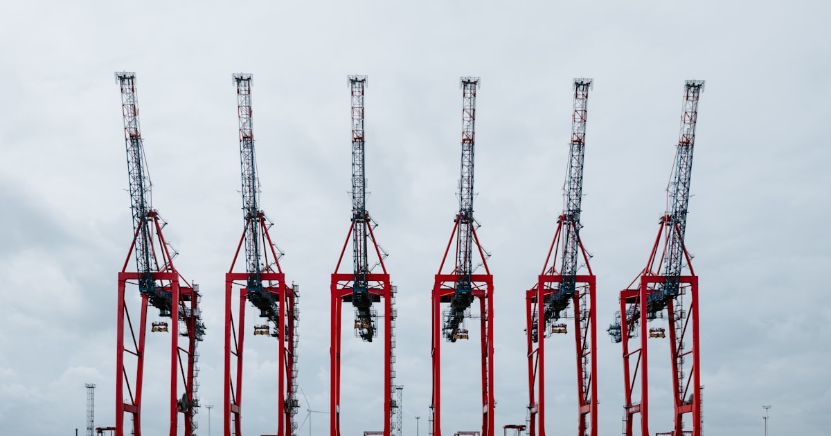 a row of red cranes sitting on top of a body of water