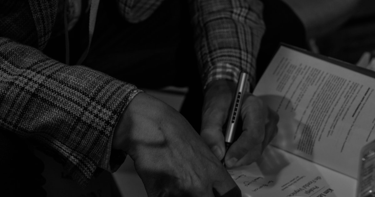 grayscale photo of person writing on paper
