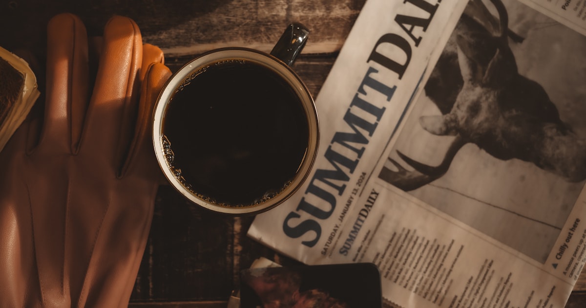 a cup of coffee next to a newspaper and a pair of gloves