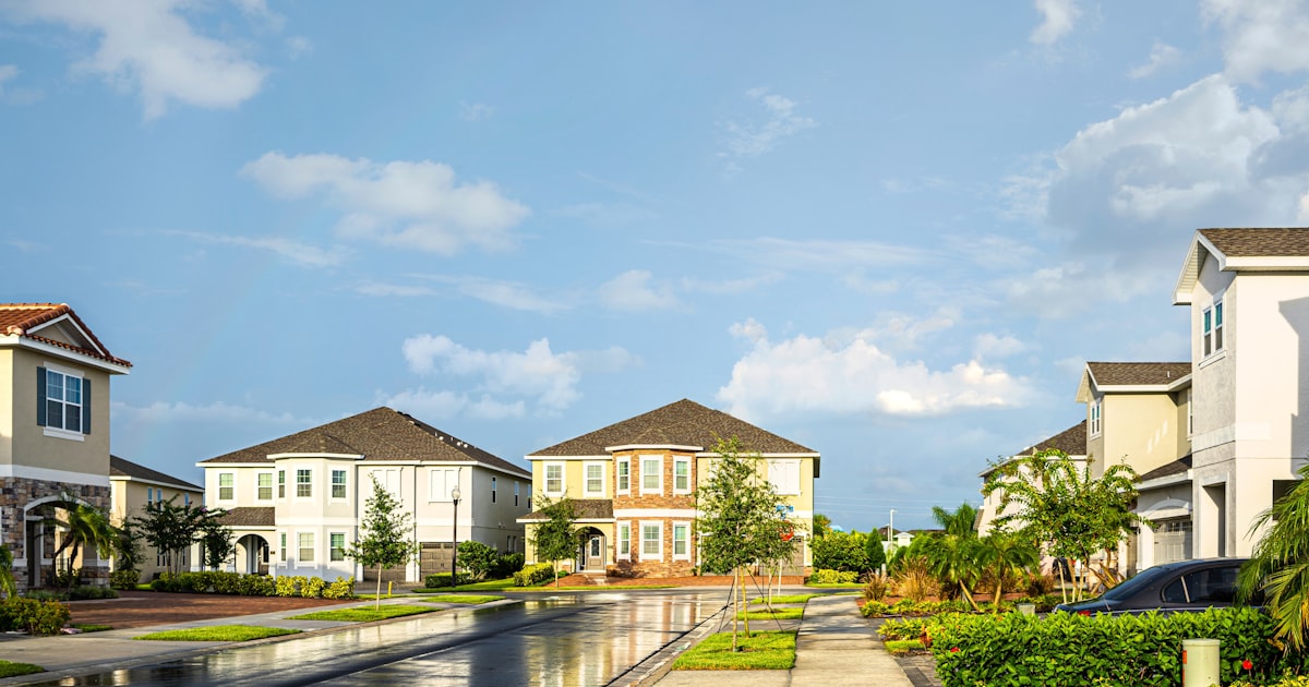 white and brown house near green trees under blue sky during daytime