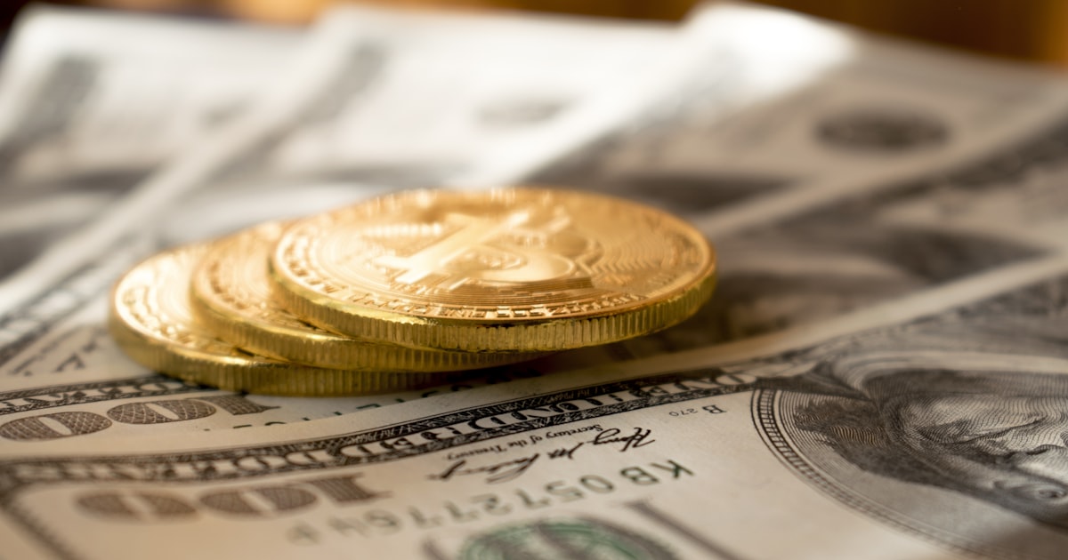 three round gold-colored coins on 100 US dollar banknotes