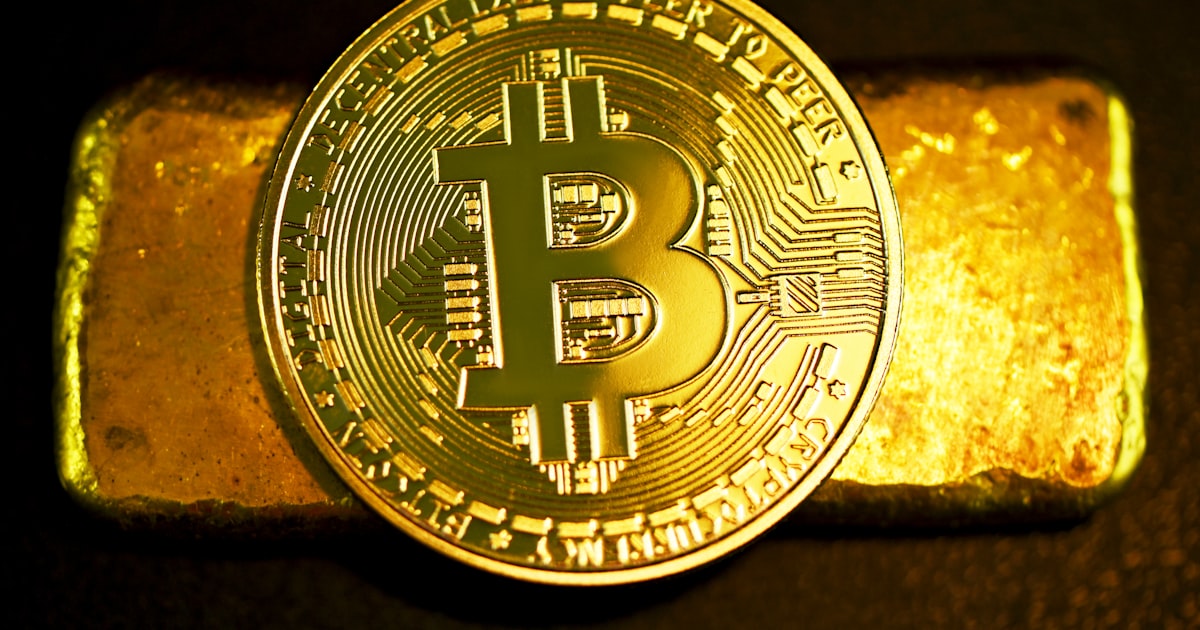 a bitcoin sitting on top of a gold bar