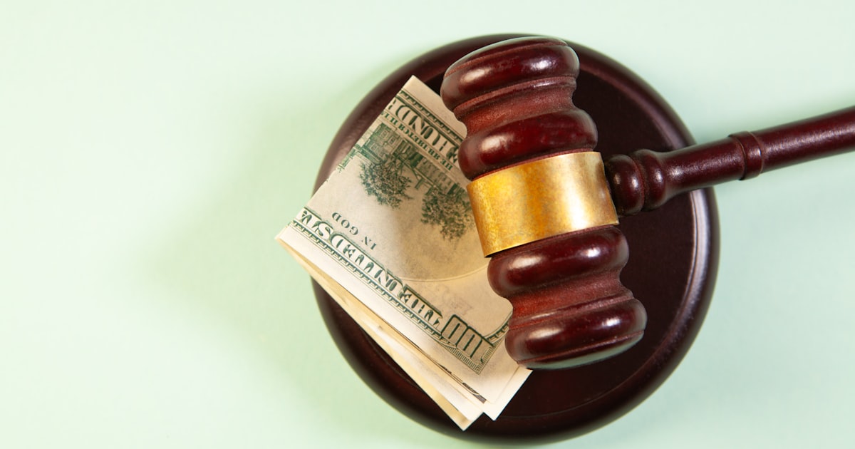 A gavel rests on a sound block with money.
