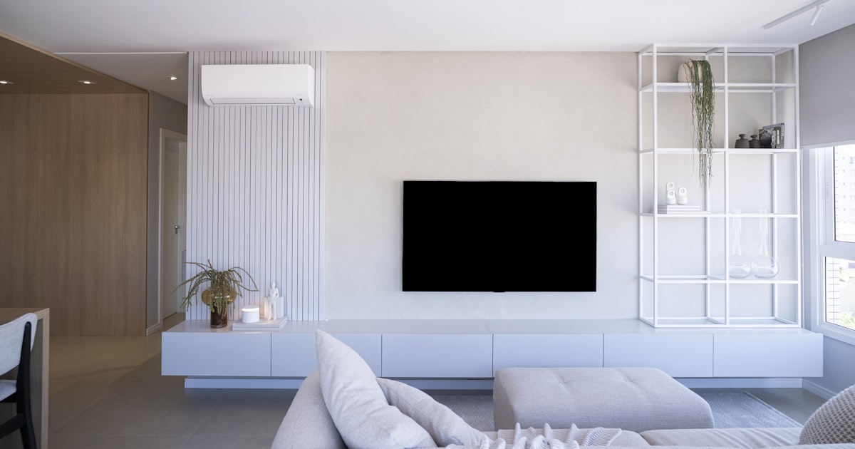 Modern living room with white furniture and large television.