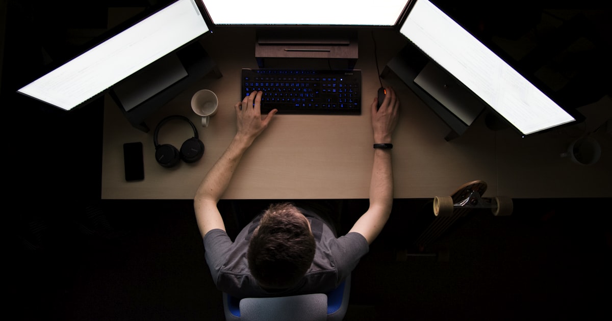 man facing three computer monitors while sitting