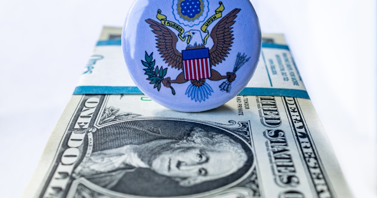 A blue button sitting on top of a one dollar bill
