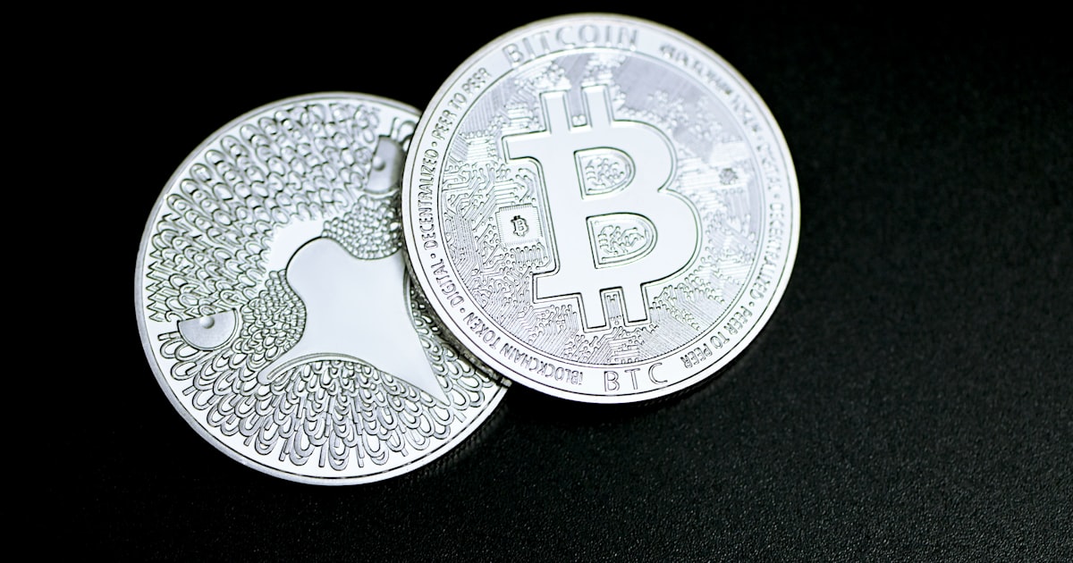 two bitcoins sitting side by side on a black surface