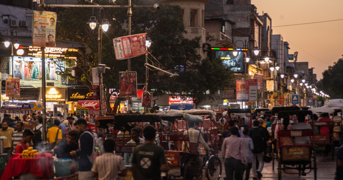 Bustling street market with people and shops at dusk.