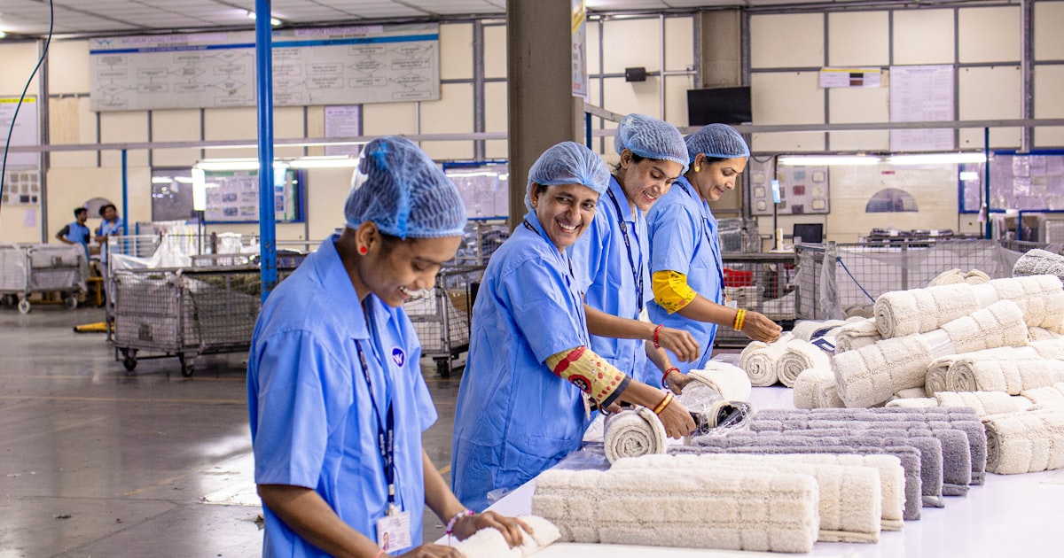 Workers sort and roll textiles in a factory.