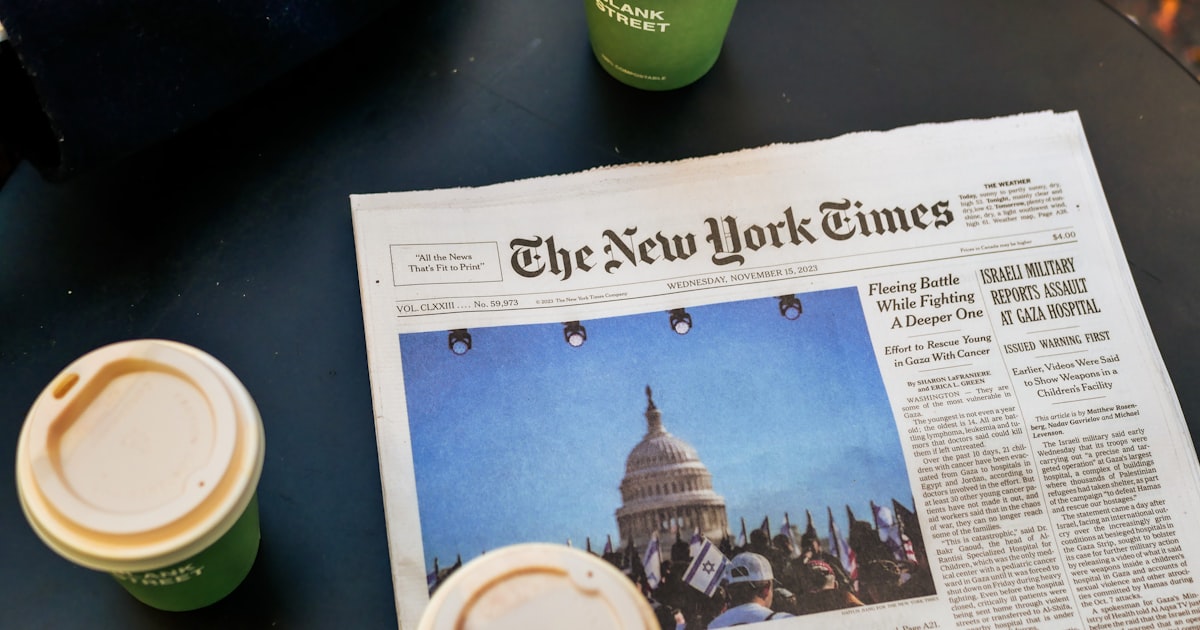 a newspaper sitting on top of a table next to two cups of coffee
