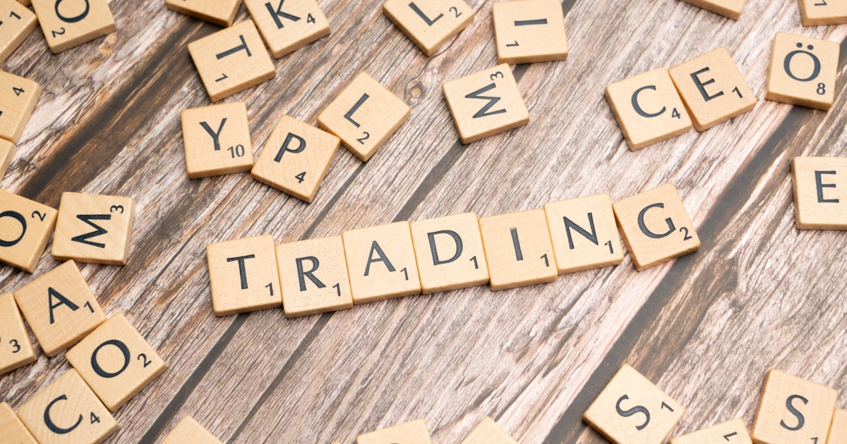 scrabble tiles spelling the word trading on a wooden surface