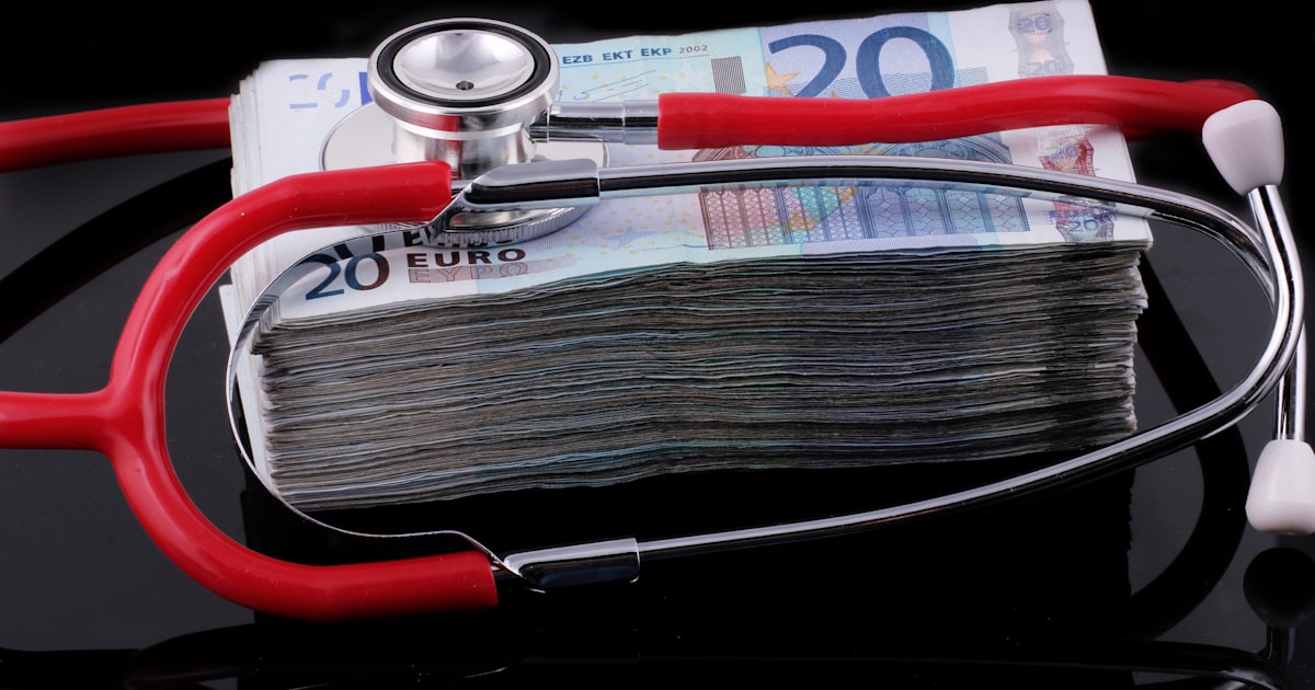 a medical stethoscope resting on a stack of money