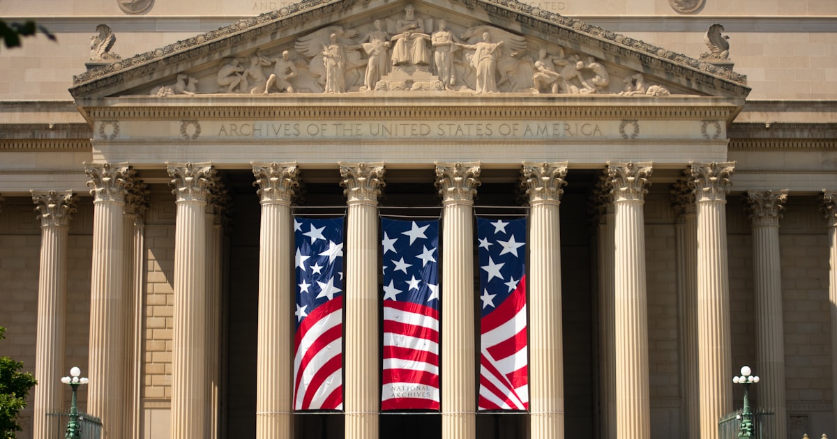a building with columns and two american flags on it
