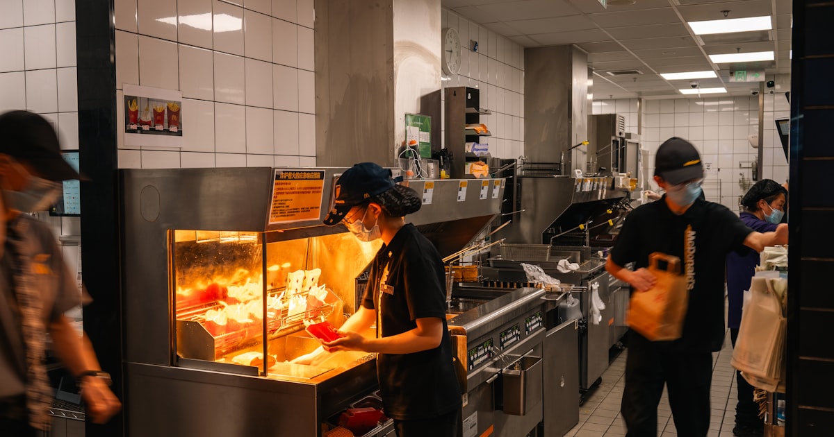 Workers preparing food in a busy restaurant kitchen.