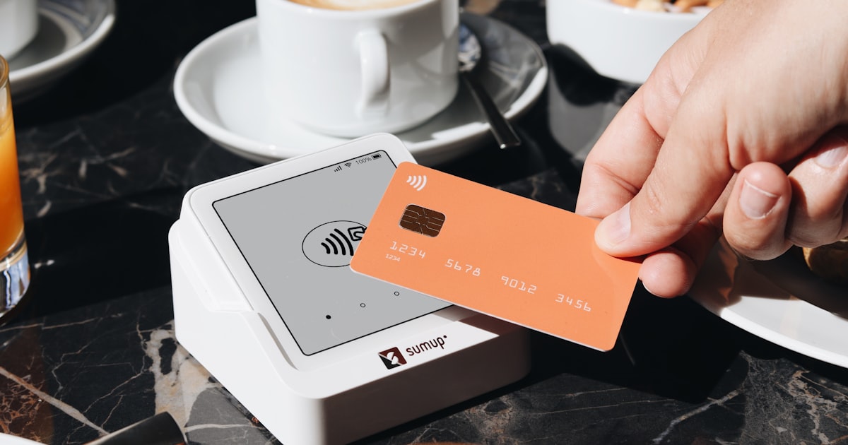A person holding a credit card over a table