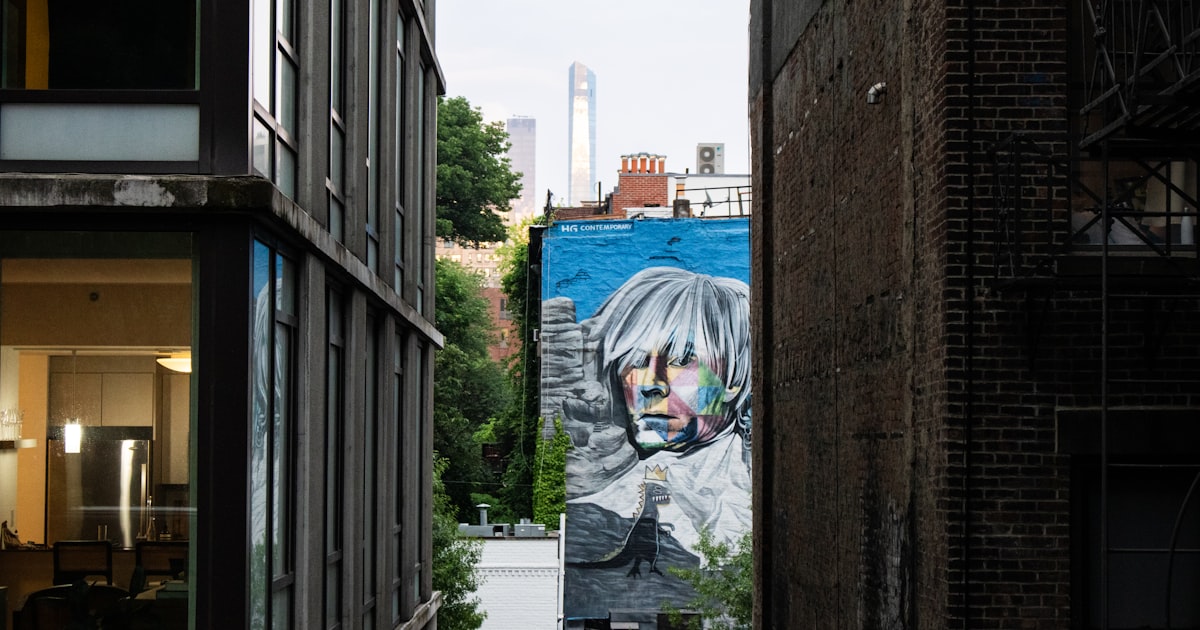 An alley way with a mural of a man's face on the side of