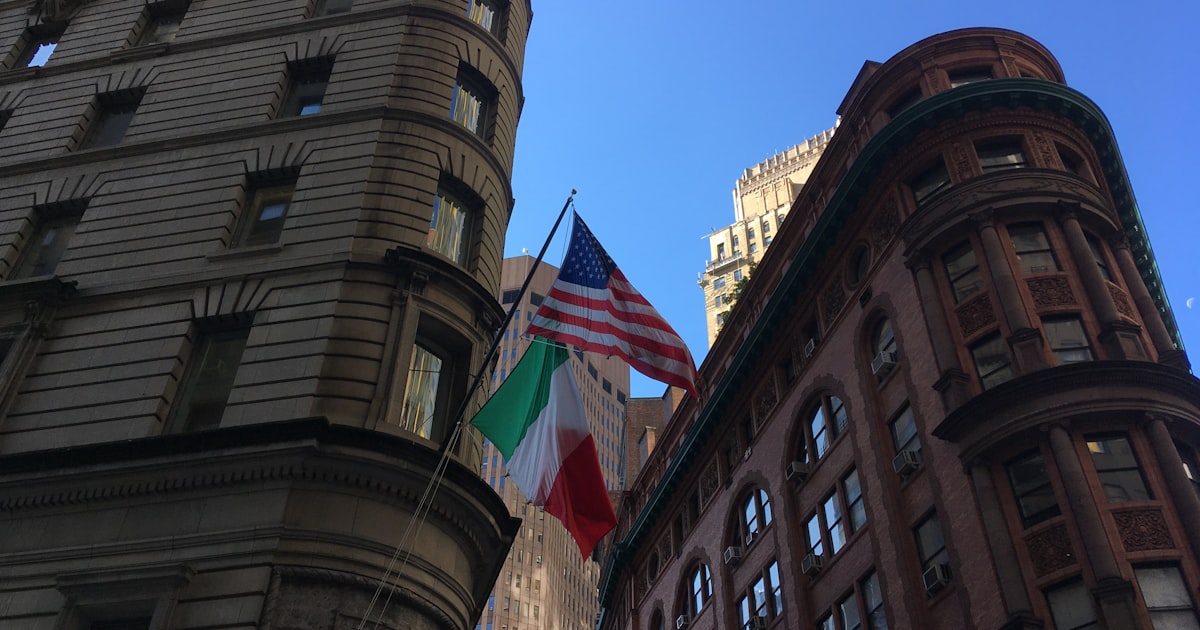 two flags are flying in front of a building