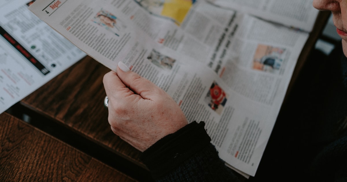 a person sitting at a table reading a newspaper