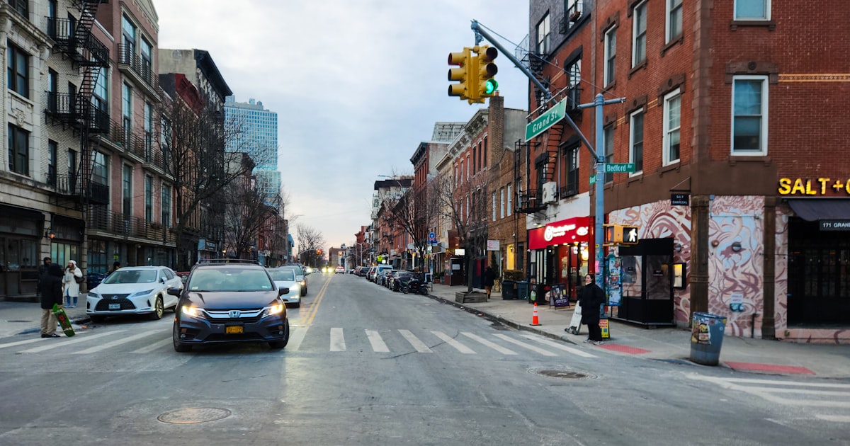 A city street filled with traffic next to tall buildings