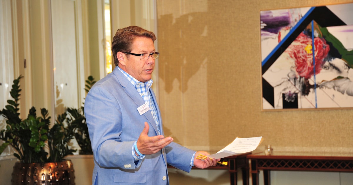 man in blue suit jacket holding white paper
