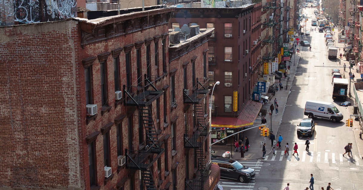 cars parked on street in between high rise buildings during daytime