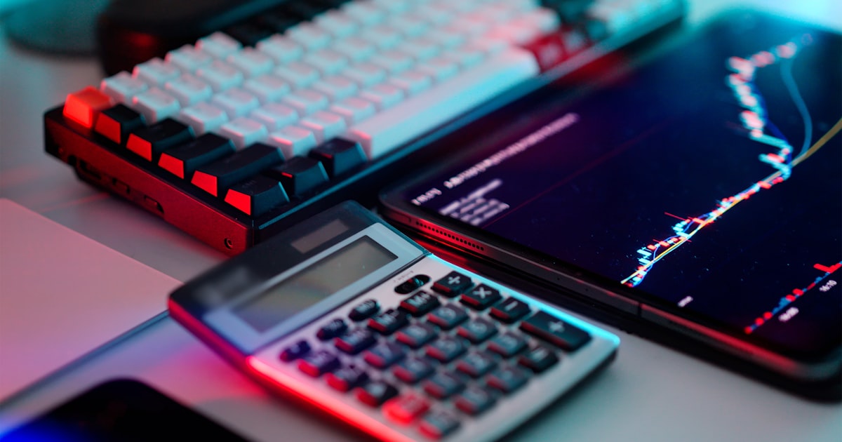 A laptop computer sitting on top of a desk next to a calculator