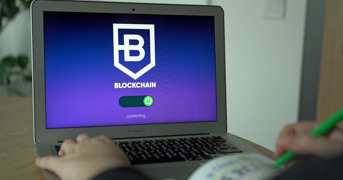 a person using a laptop with a blockchain logo on the screen