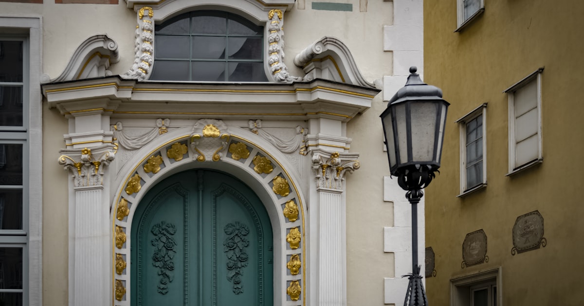 Ornate teal door with ornate architectural details and lamppost.