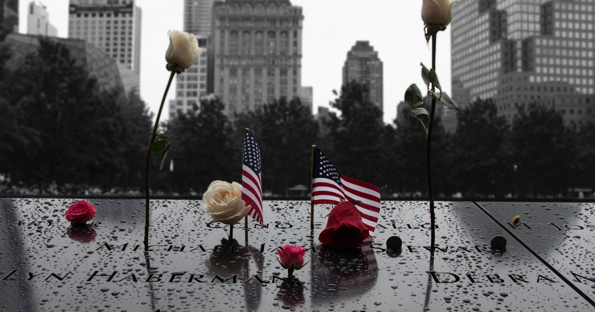a group of flags on a stone surface with flowers and a city in the background